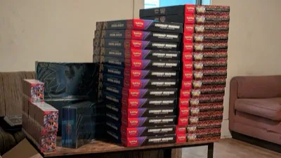Tall stacks of Pokémon collection boxes beside black Elite Trainer Boxes