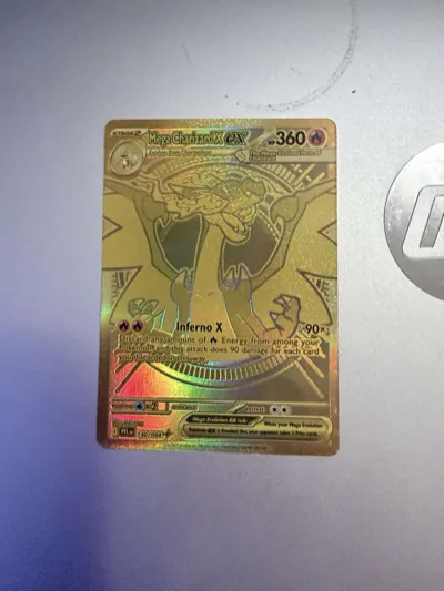 Gold-colored Mega Charizard X ex card resting on a silver laptop