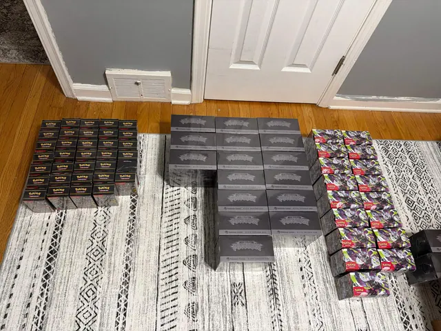 Pokémon Elite Trainer Boxes and booster boxes arranged in three groups on a patterned rug.