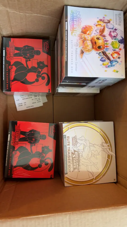 An open carton holding red-and-black Pokémon boxes and white collection boxes