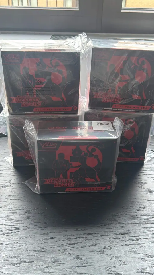 Red-and-black Pokémon boxes displayed together in clear protective cases