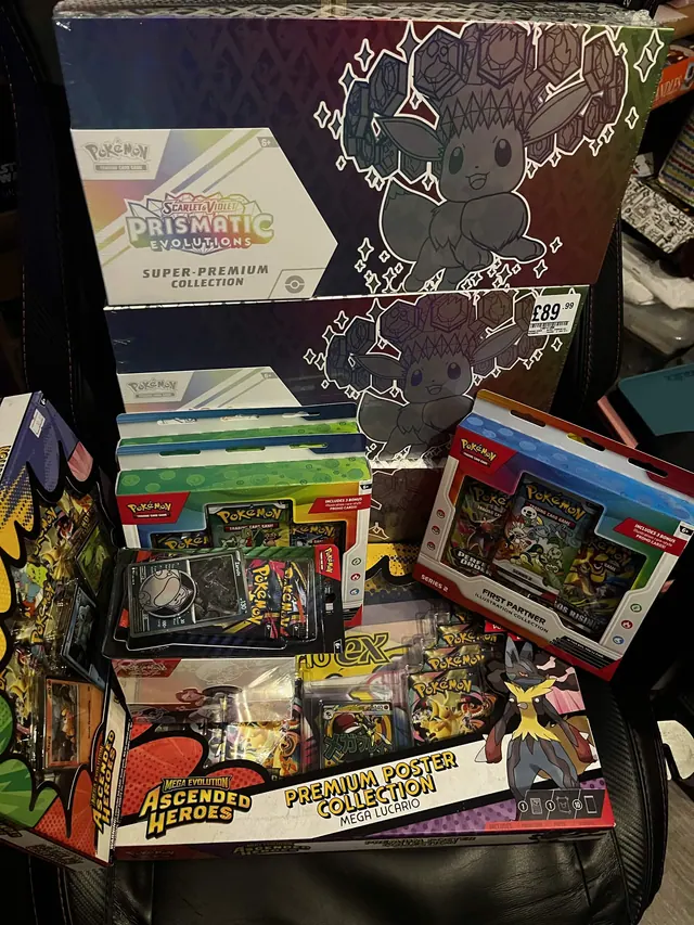 Prismatic Evolutions boxes displayed with Pokémon tins and collection packs.