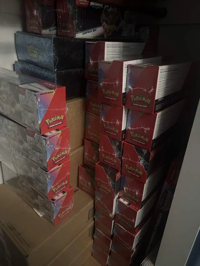 Tall stacks of red and reflective Pokémon boxes beside delivery cartons