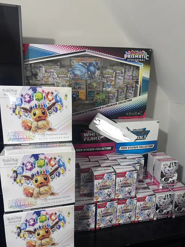 Prismatic Evolutions Elite Trainer Boxes displayed with assorted Pokémon collections.