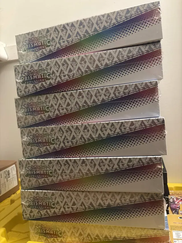 A tall stack of sealed Prismatic Evolutions Super-Premium Collection boxes.