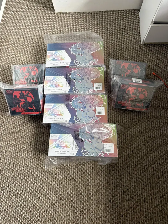 Wrapped Prismatic Evolutions boxes surrounded by Destined Rivals boxes on a carpet.