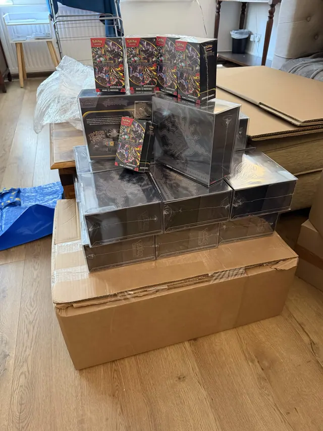 Dark and reflective Pokémon collection boxes arranged on top of shipping cartons