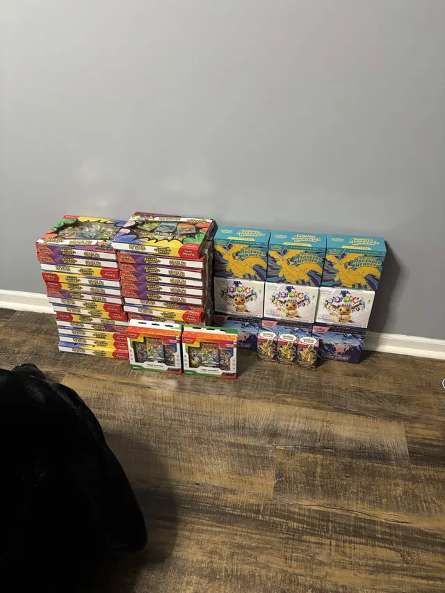 Pokémon boxed collections lined up against a wall on a wooden floor.