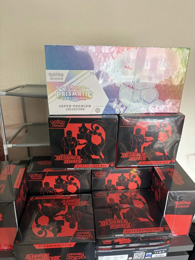 A Prismatic Evolutions box displayed above a stack of Destined Rivals boxes.