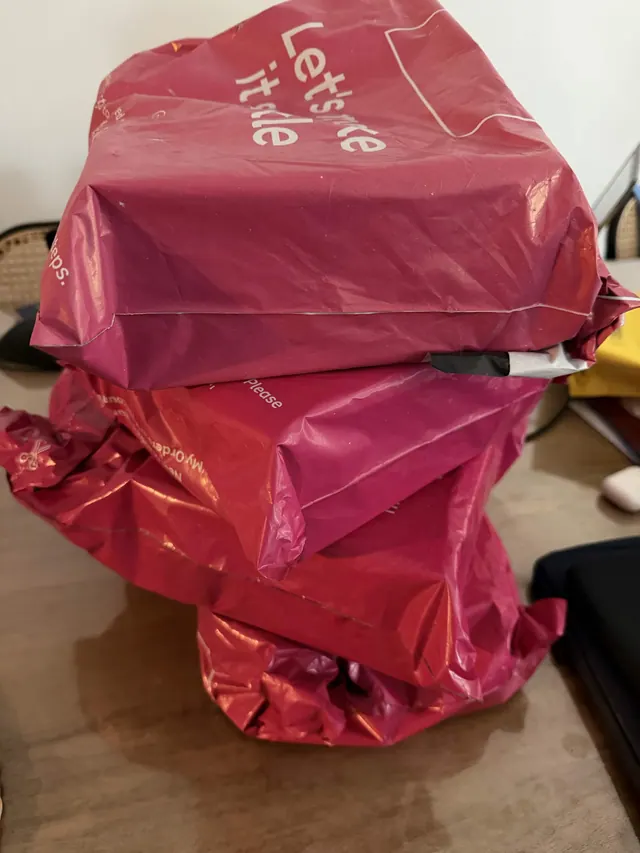 Several large red shopping bags stacked together on a tabletop