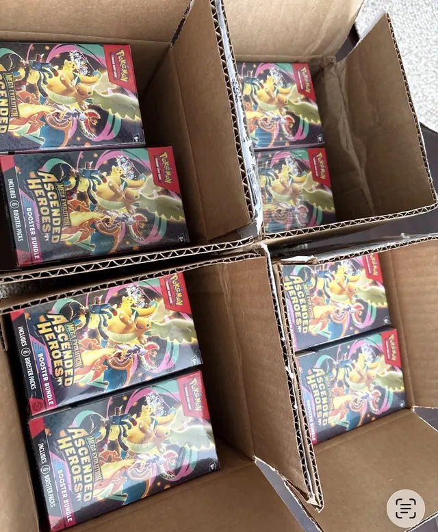 Four open cartons filled with sealed Pokémon card boxes.