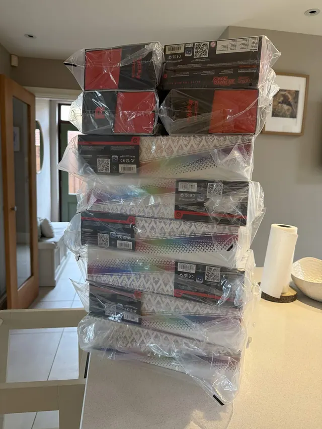 A tall stack of wrapped Pokémon boxes topped with Destined Rivals boxes.