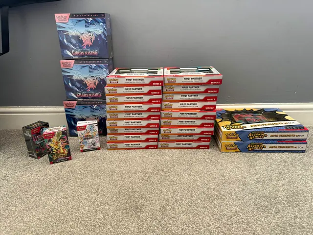Chaos Rising Elite Trainer Boxes, First Partner collections and booster bundles arranged on a floor.