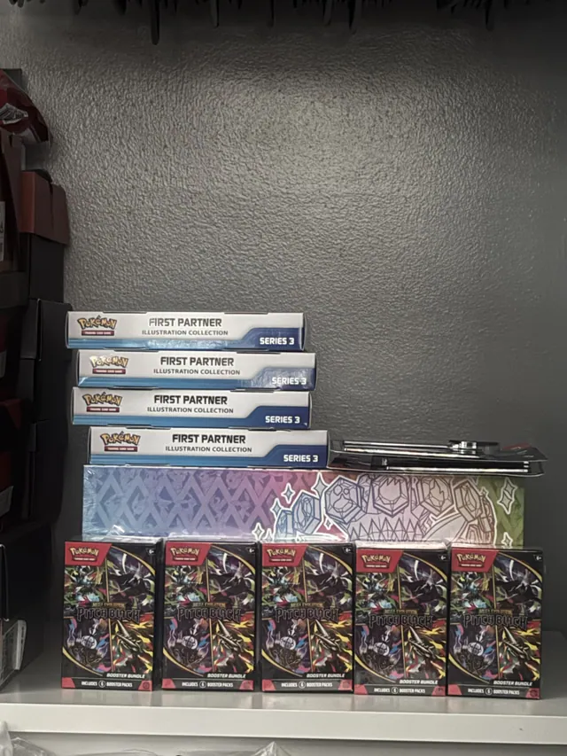 Pokémon booster boxes and blue-and-white collection boxes grouped on a shelf