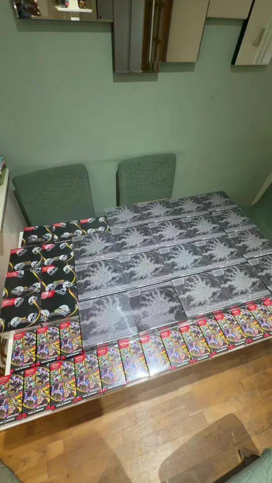 Rows of sealed Pokémon trading card products covering a wooden table.