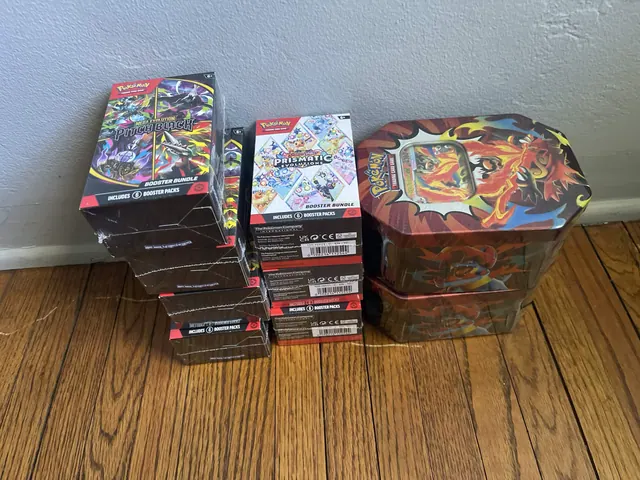 Sealed Pokémon tins and boxed card collections arranged on a wooden surface.