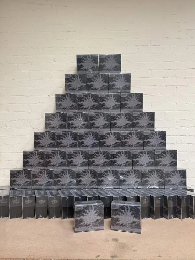 A pyramid of sealed Pokémon boxes with smaller boxes across the base.