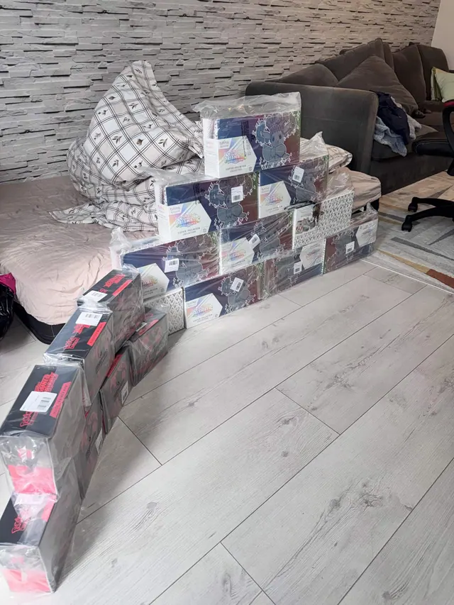 Pokémon collection boxes stacked along a sofa and across a wooden floor