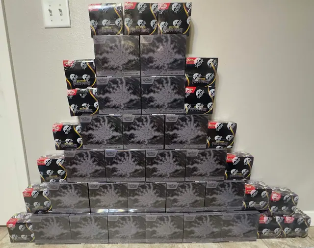 A pyramid of black Pokémon boxes flanked by smaller illustrated tins