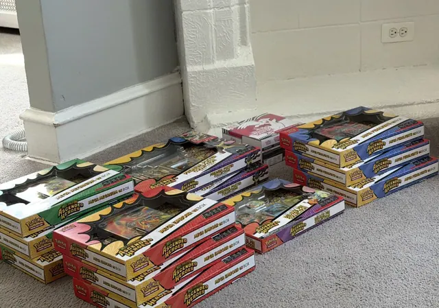 Long colorful Pokémon collection boxes arranged in several piles on a carpet