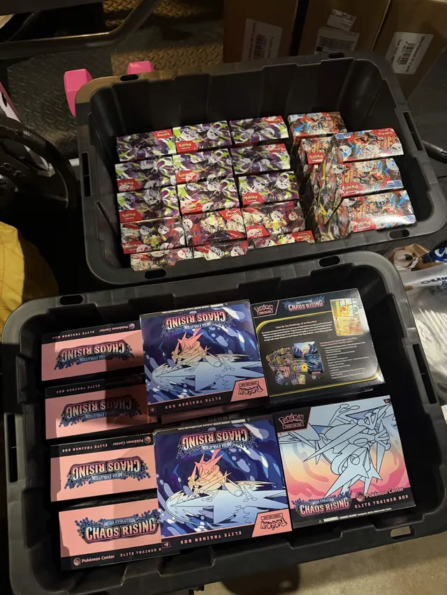 Two open storage cases filled with Pokémon card tins and packaged collections.
