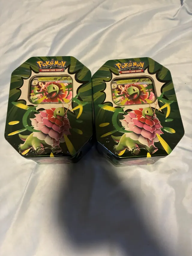 Two green Pokémon tins featuring Mega Meganium ex on a white surface.